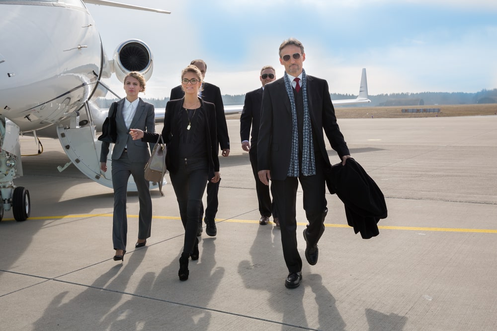 Group of millionaires alighted from a private jet walking by