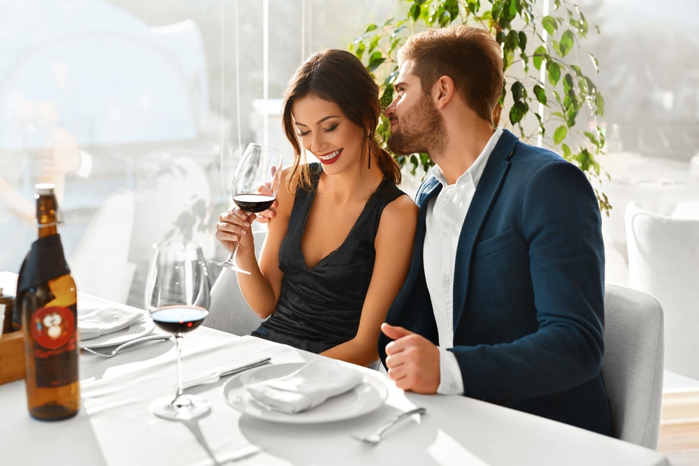 Paar verliebt. Glückliche romantische lächelnde elegante Menschen, die Abendessen haben, Wein trinken, Feiertag, Jahrestag oder Valentinstag in einem Gourmet-Restaurant feiern. Romantik-, Beziehungs-Konzept.