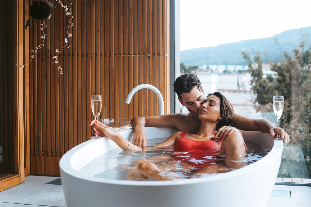 Beautiful sugar daddy and sugar baby couple enjoying a relaxing bath with champagne