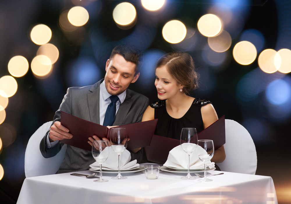 Lächelnde Sugar-Dating-Paare im Restaurant mit Blick auf die Speisekarte